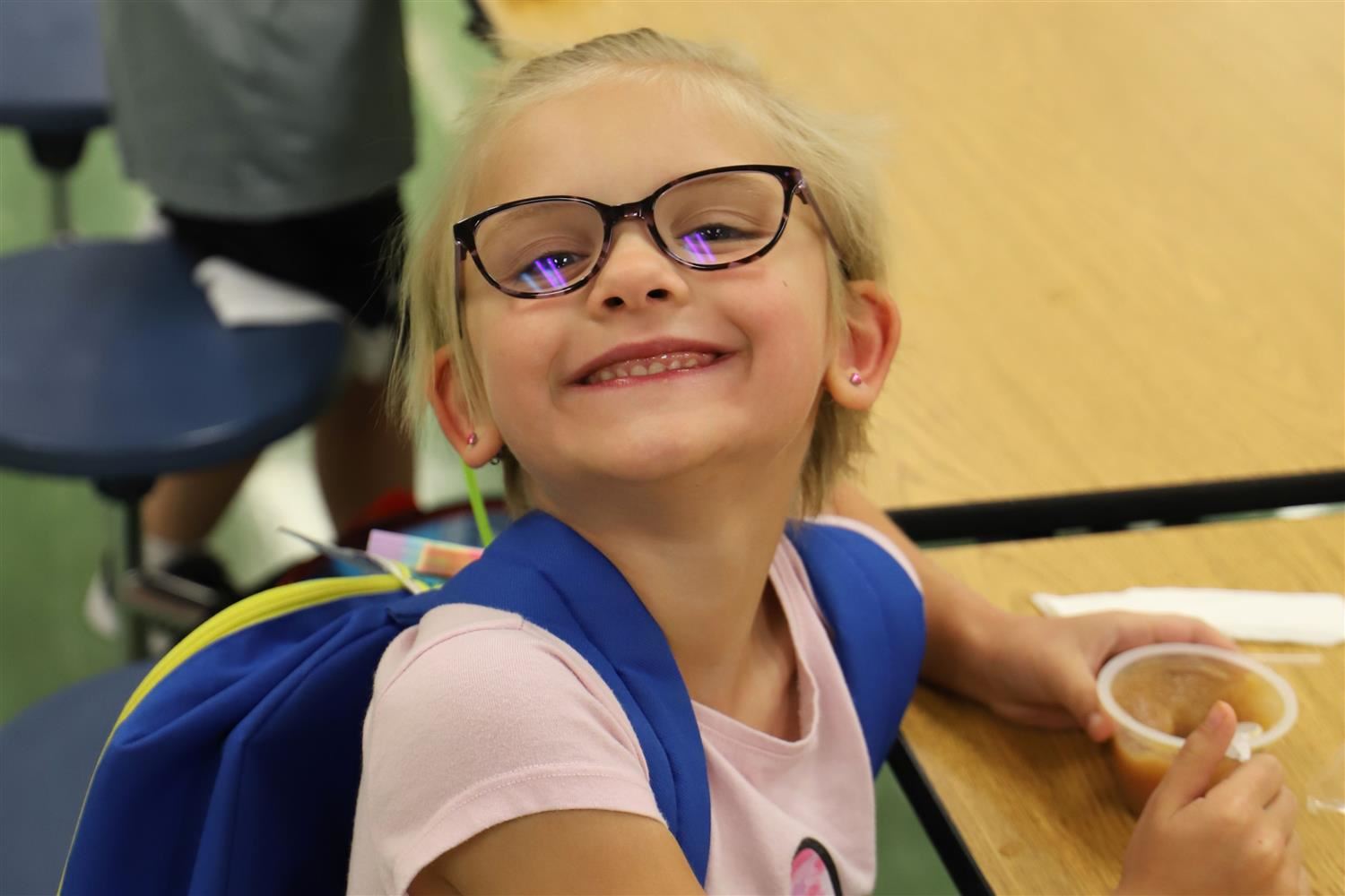 Smiling Engleman Elementary student in the cafeteria with an applesauce cup.